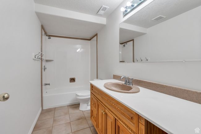 Bathroom featuring toilet, vanity, tub / shower combination, tile patterned flooring, and baseboards | Image 21