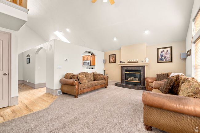 Living area featuring light carpet, arched walkways, lofted ceiling, a tile fireplace, and recessed lighting | Image 10