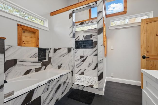 Full bathroom with baseboards, a walk in shower, a bath, and wood finished floors | Image 23