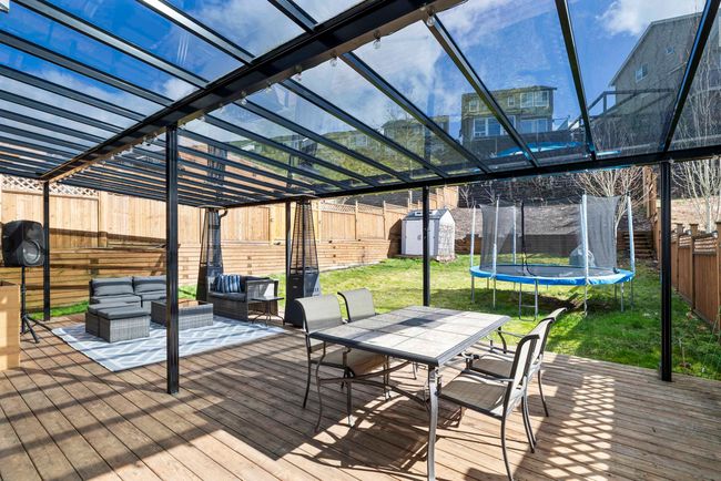 Deck with an outbuilding, a shed, outdoor dining area, a yard, and a trampoline | Image 15
