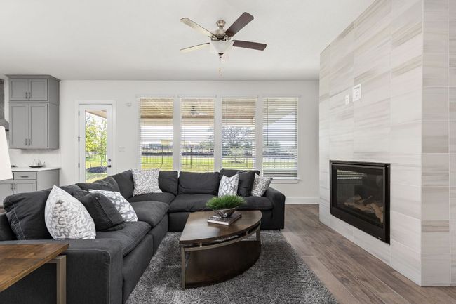 Living area featuring dark wood-type flooring, a ceiling fan, a glass covered fireplace, and baseboards | Image 19