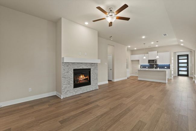 Living room with a fireplace, a ceiling fan, and recessed lighting. | Image 10