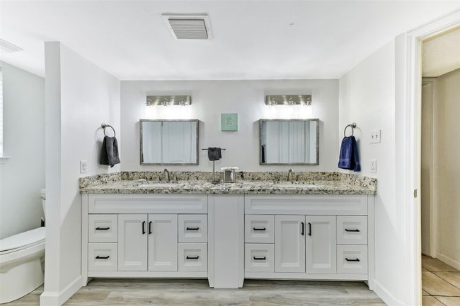 The primary bathroom is accented with white cabinetry and neutral-toned flooring, creating a clean and inviting atmosphere. | Image 16