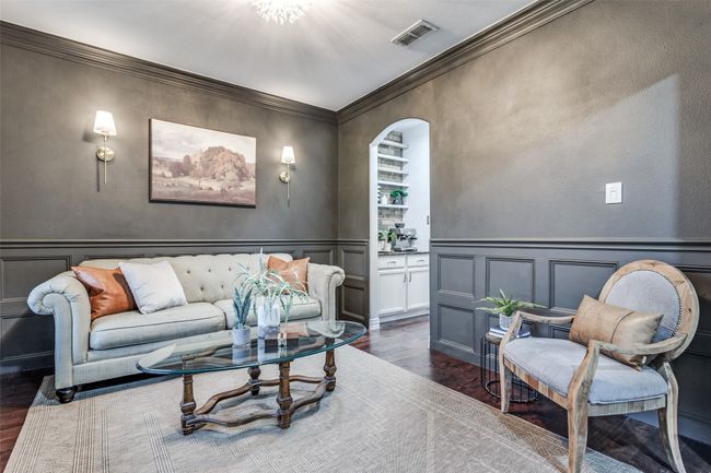 Living room featuring dark wood finished floors, a decorative wall, arched walkways, ornamental molding, and wainscoting | Image 8