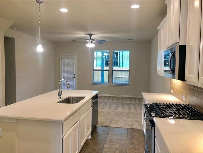 Kitchen with stainless steel microwave, gas range, carpet, dishwasher, and light countertops | Image 5