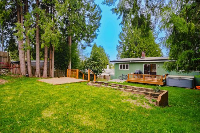 Rear view of house with a fenced backyard, a yard, a wooden deck, a patio, and a hot tub | Image 33