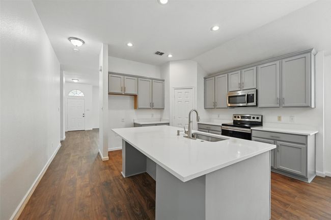 Kitchen featuring gray cabinets, stainless steel appliances, a sink, dark wood finished floors, and vaulted ceiling | Image 13