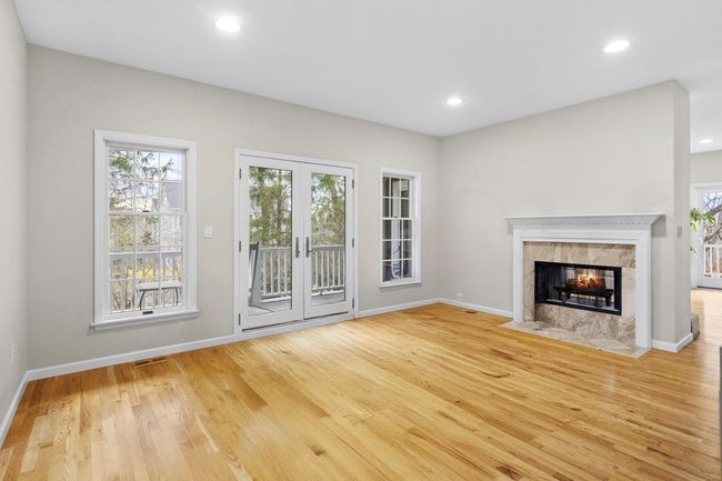 The elegant living room features a marble-surround dual-sided fireplace, rich hardwood floors, and French doors opening to the wraparound porch. (will be furnished) | Image 16