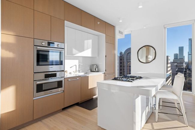 Kitchen with light countertops, light wood-style flooring, appliances with stainless steel finishes, a view of city, and a sink | Image 4