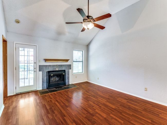 Unfurnished living room with plenty of natural light, wood finished floors, and high vaulted ceiling | Image 8