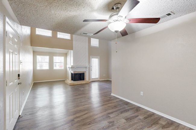 Unfurnished living room with visible vents, a textured ceiling, wood finished floors, and a fireplace | Image 16