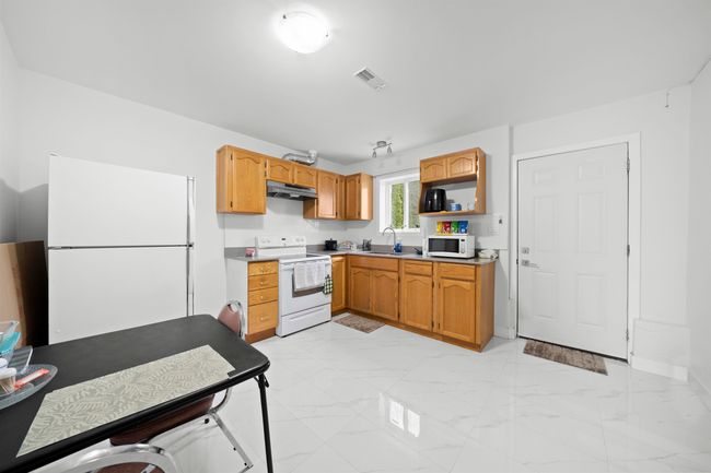 Kitchen featuring white appliances, under cabinet range hood, marble finish floor, a sink, and visible vents | Image 20
