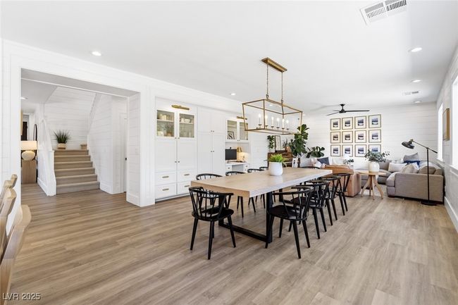 Dining area featuring light wood-style flooring, visible vents, stairs, ceiling fan, and wooden walls | Image 18