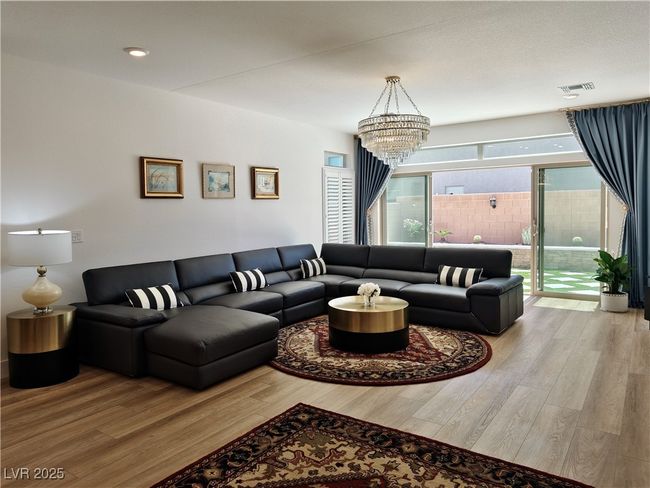 Living area featuring wood finished floors, visible vents, and a notable chandelier | Image 9