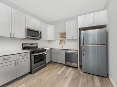 Kitchen with light hardwood / wood-style flooring, appliances with stainless steel finishes, sink, gray cabinets, and decorative backsplash | Image 2