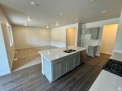 Kitchen featuring dishwasher, an island with sink, dark hardwood / wood-style floors, light stone countertops, and sink | Image 3