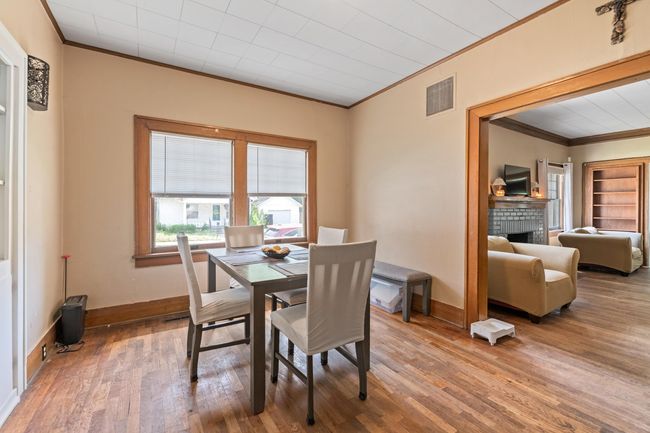 Dining area featuring ornamental molding, wood finished floors, baseboards, and a brick fireplace | Image 28