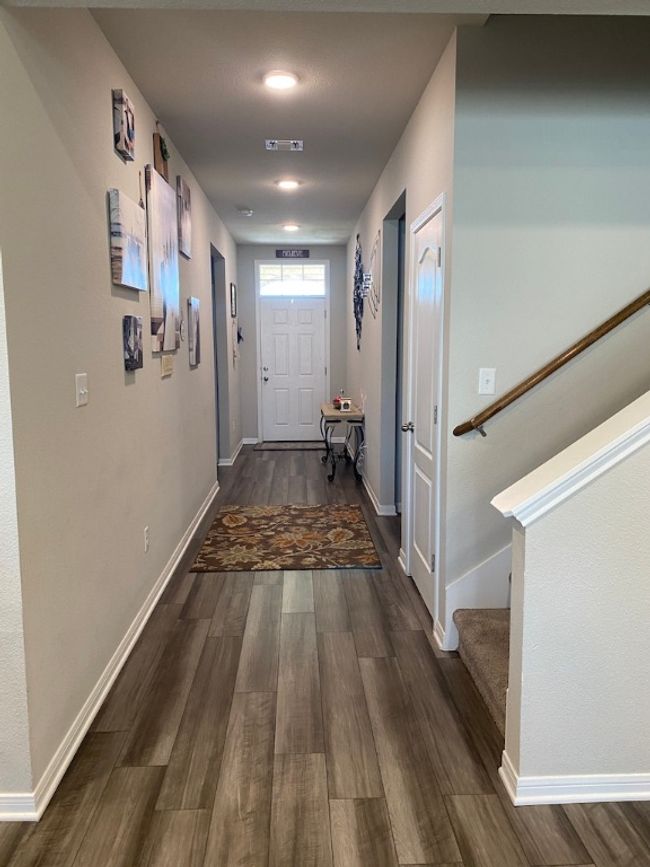 Hall featuring wood finished floors, baseboards, visible vents, and stairway | Image 9