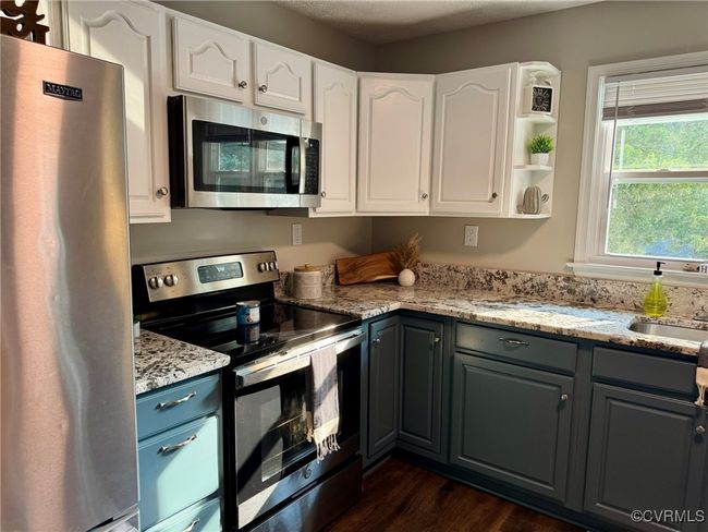 Kitchen featuring appliances with stainless steel finishes, white cabinetry, and light stone counters | Image 6