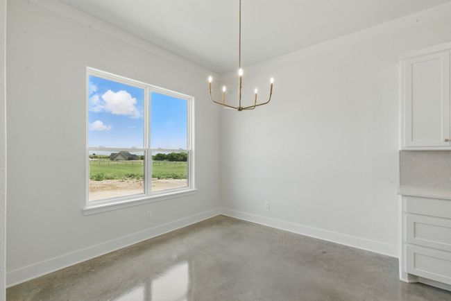 Unfurnished dining area with a chandelier, finished concrete flooring, and baseboards | Image 9