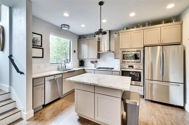 Kitchen featuring appliances with stainless steel finishes, wall chimney exhaust hood, recessed lighting, light stone countertops, and light wood-type flooring | Image 5