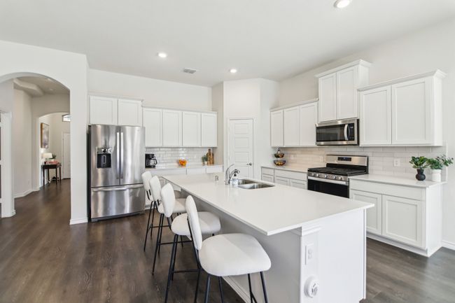 Kitchen featuring dark wood-style flooring, a center island with sink, visible vents, stainless steel appliances, and a sink | Image 10