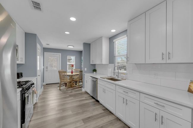 Kitchen with stainless steel appliances, backsplash, a sink, light wood-style floors, and visible vents | Image 14