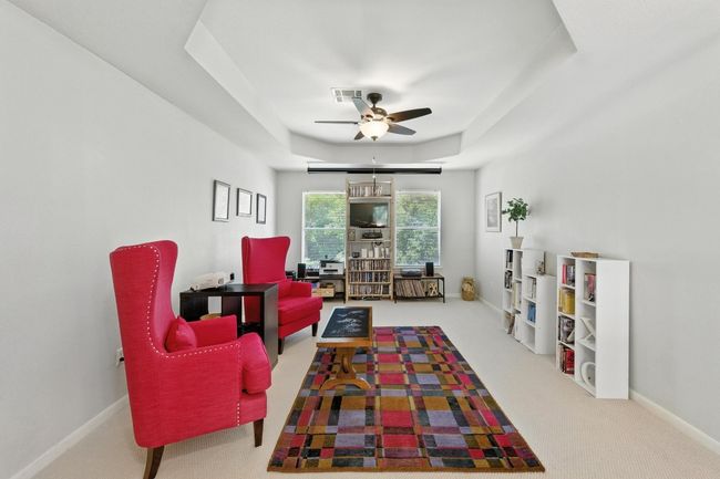 Carpeted living area with ceiling fan and a raised ceiling | Image 15