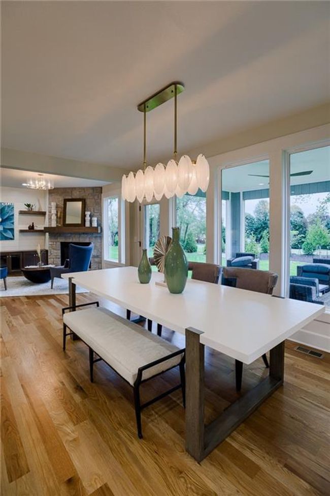 Dining room featuring light wood-type flooring, a chandelier, and a stone fireplace | Image 10