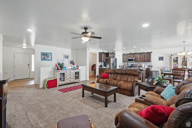Living room featuring light carpet, recessed lighting, ceiling fan with notable chandelier, and baseboards | Image 9