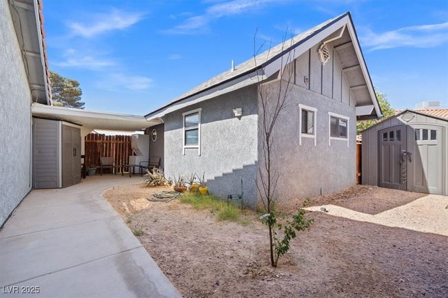 View of side of property featuring a storage shed, an outbuilding, fence, a patio, and stucco siding | Image 43