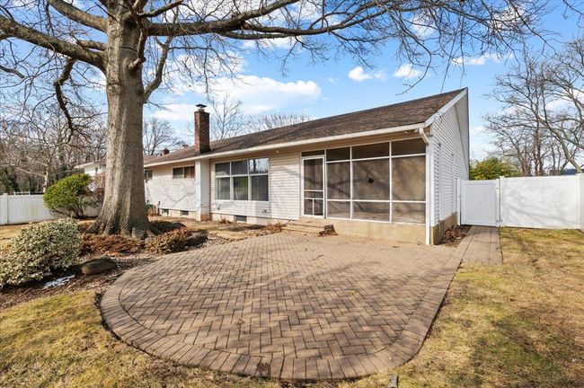 Rear view of house with a sunroom, a yard, and a patio area | Image 17