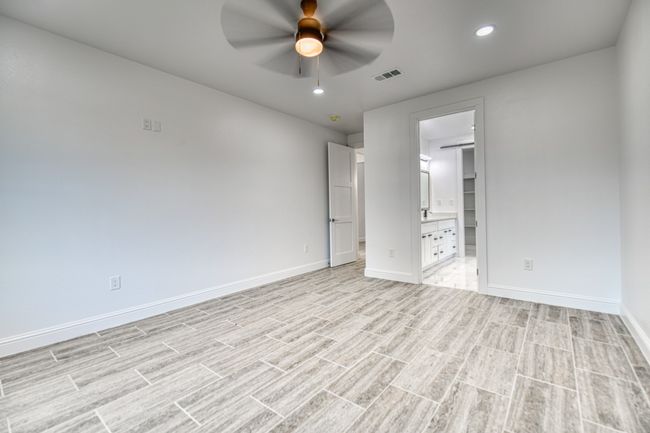 Unfurnished bedroom featuring a walk in closet, ensuite bathroom, light wood-type flooring, and ceiling fan | Image 23