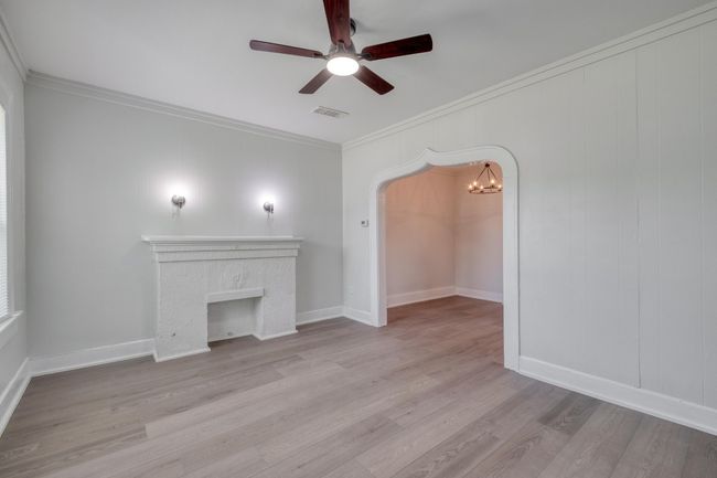 Unfurnished room featuring ornamental molding, a ceiling fan, wood finished floors, arched walkways, and a chandelier | Image 24