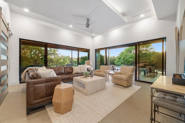 Living room featuring light tile patterned flooring, ceiling fan, a towering ceiling, and a wealth of natural light | Image 12