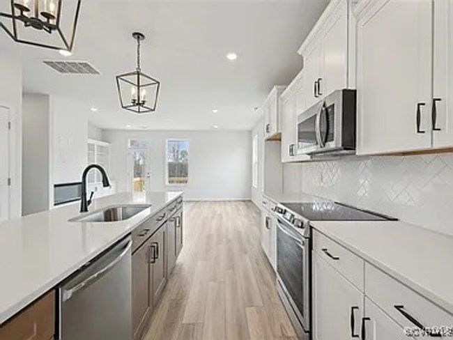 Kitchen featuring appliances with stainless steel finishes, light wood-style flooring, light countertops, hanging light fixtures, and recessed lighting | Image 15