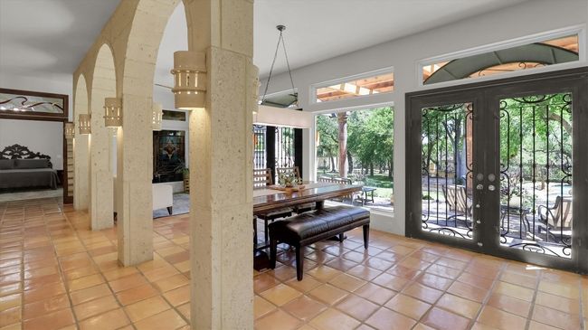 Dining space with arched walkways, plenty of natural light, light tile patterned floors, and french doors | Image 11