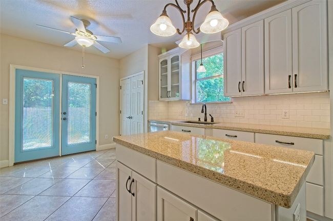 Kitchen featuring french doors, backsplash, glass insert cabinets, stainless steel dishwasher, and white cabinets | Image 17