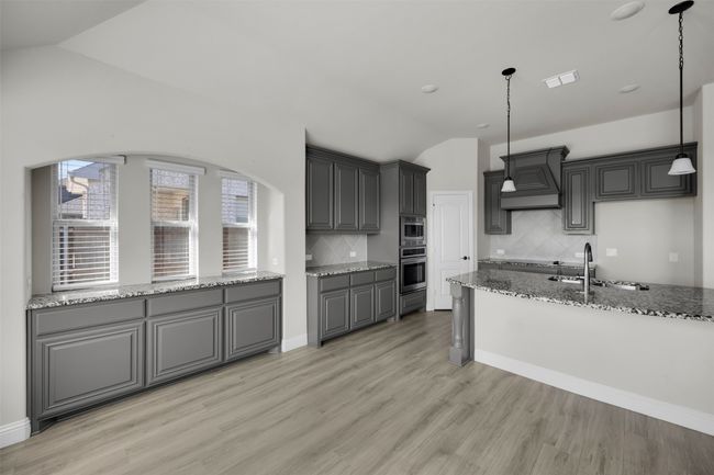 Kitchen featuring appliances with stainless steel finishes, decorative light fixtures, vaulted ceiling, and custom exhaust hood | Image 17
