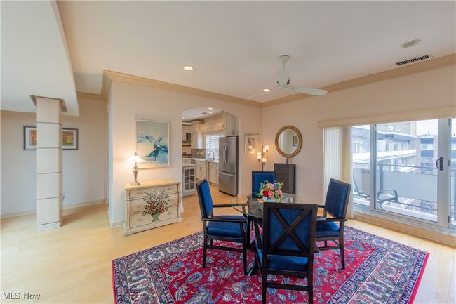 Dining area off kitchen with sliders to balcony. with light wood floors, recessed lighting, ceiling fan, crown molding. and built-ins | Image 7