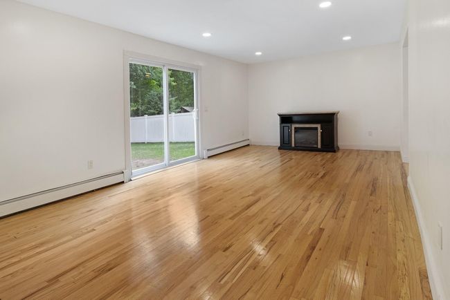 Unfurnished living room featuring baseboard heating, light wood finished floors, a fireplace, recessed lighting, and baseboards | Image 8