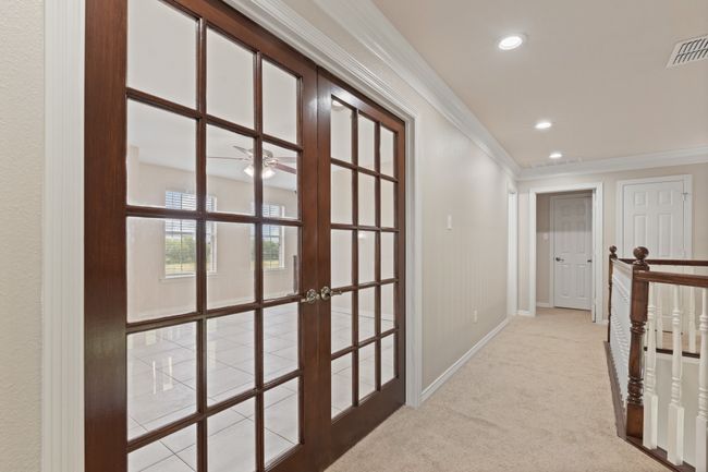 Upstairs hallway showing double doors into a bonus room, game room, second living area, office bedroom, all your choice of course! View looking down the hall back to the staircase landing into the first bedroom with full bath. | Image 26