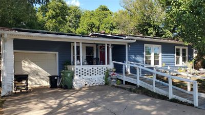 Ranch-style house featuring a porch and a garage | Image 1