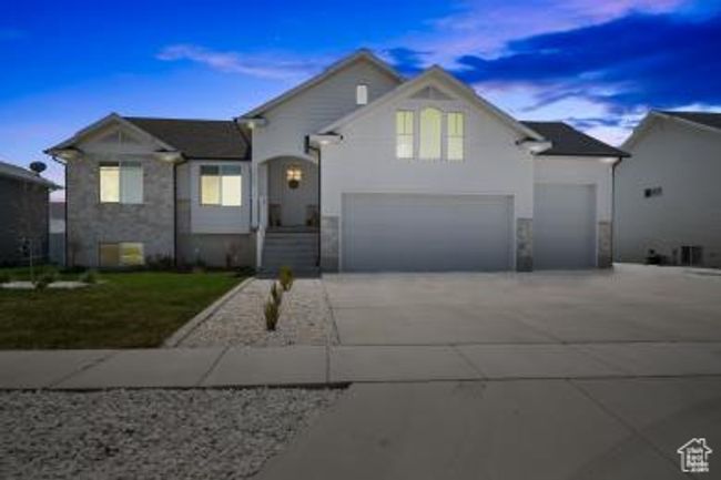 Tri-level home featuring stone siding, an attached garage, and concrete driveway | Image 5