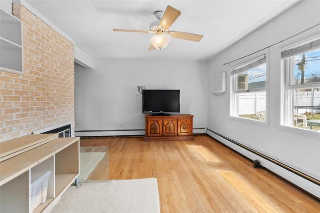 Unfurnished living room featuring a brick fireplace, a baseboard heating unit, ceiling fan, a baseboard radiator, and light wood-style flooring | Image 18