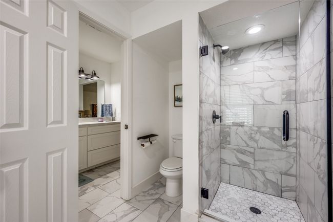 Bathroom with a shower stall, marble look tile flooring, vanity, and toilet | Image 13