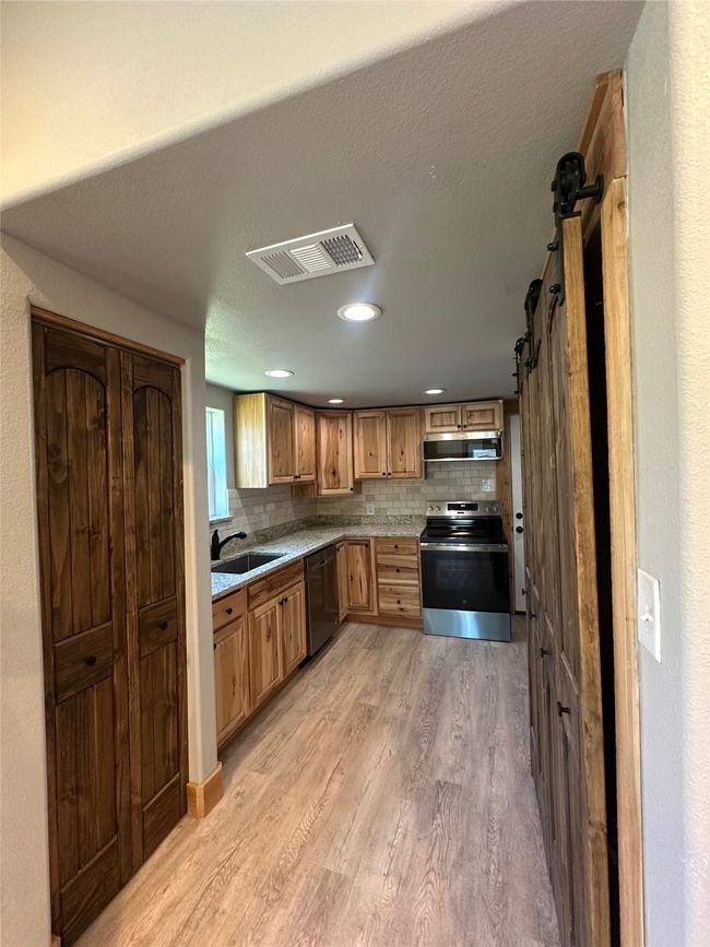 Kitchen featuring backsplash, a sink, stainless steel appliances, visible vents, and light wood-style floors | Image 21