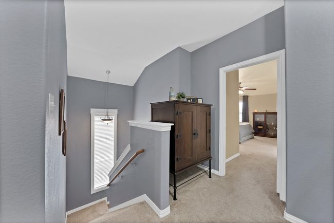 Hallway featuring an upstairs landing, vaulted ceiling, plenty of natural light, light colored carpet, and baseboards | Image 28
