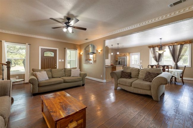 Living room featuring baseboards, a ceiling fan, healthy amount of natural light, dark wood-style floors, and ornamental molding | Image 5