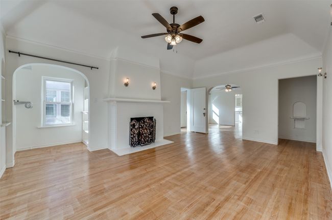 Unfurnished living room featuring arched walkways, a ceiling fan, and a brick fireplace | Image 21